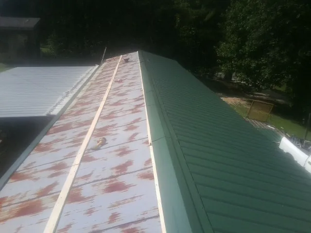 Old rusted panels beside newly installed green metal roofing — Wind Damage Roof Repair by Roofing Brothers in Collinsville